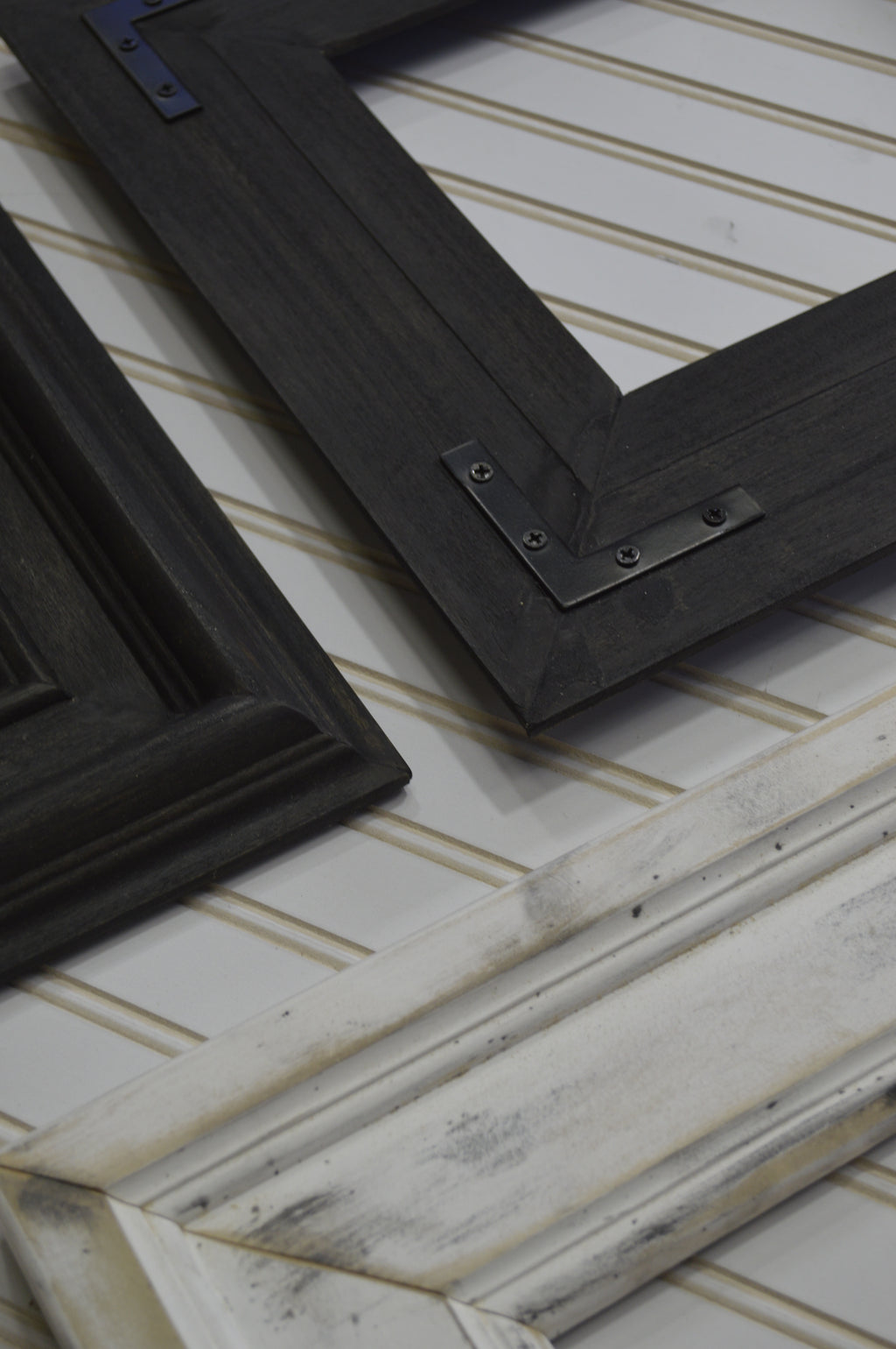 Two black picture frames on a textured white surface with gold accents