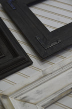 Two black picture frames on a textured white surface with gold accents